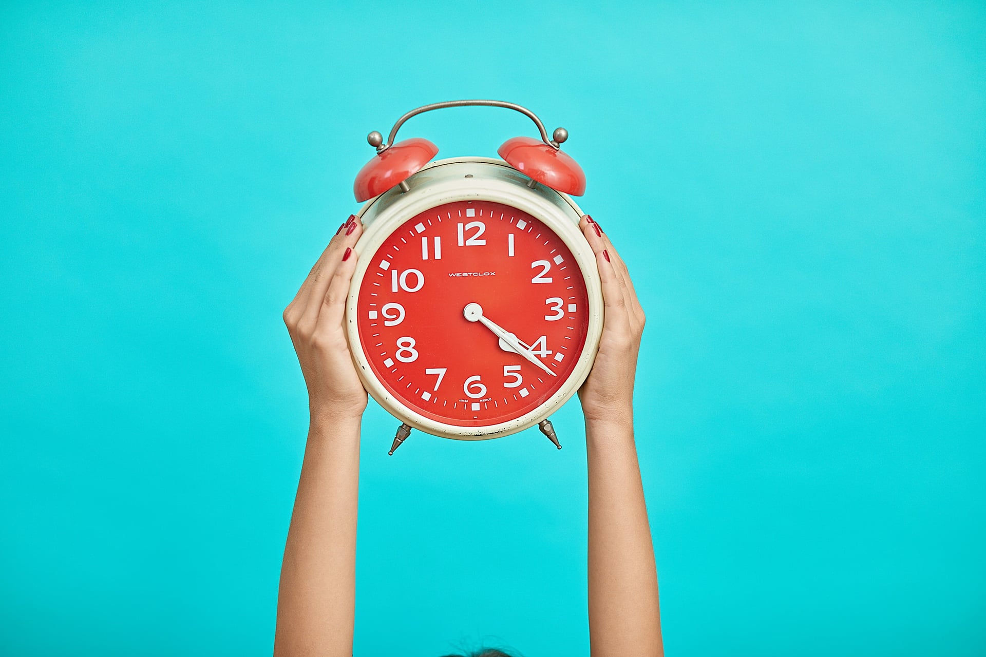 Die Hände der Frau halten die Uhr hoch