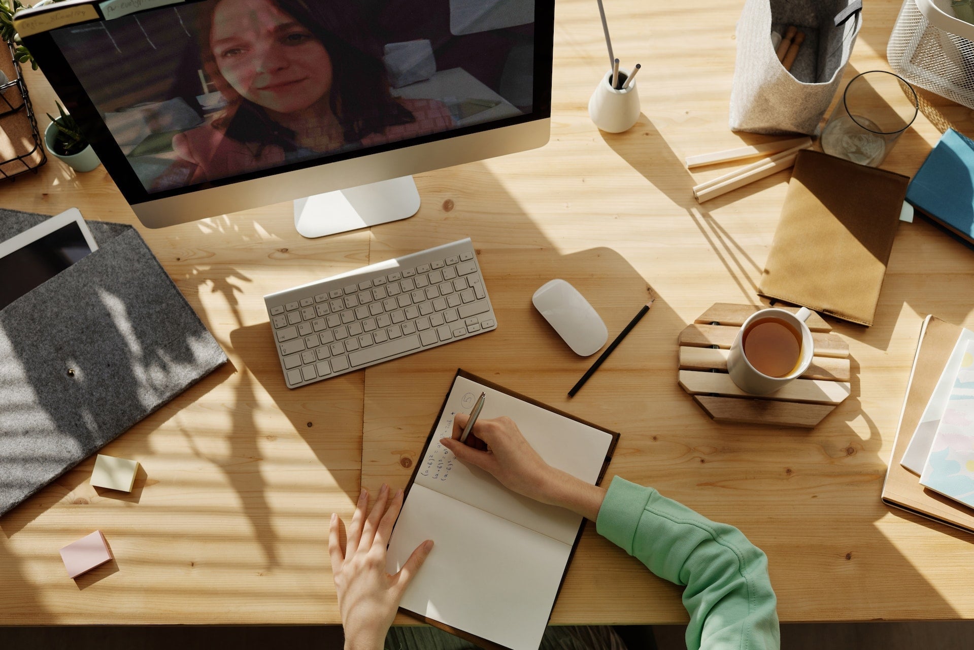 bild von jemandem, der mit der hand notizen schreibt, während er mit jemandem per videokonferenz auf einem imac spricht